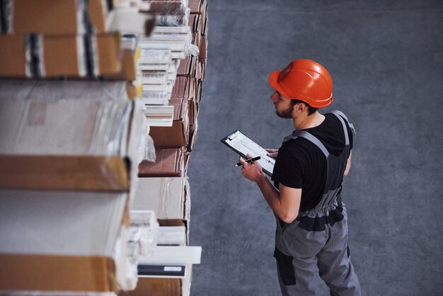 Opslagmedewerker in uniform en notitieblok in handen controleert de productie.