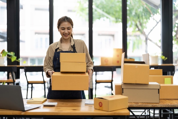 Opstarten MKB MKB ondernemer MKB of freelance Aziatische vrouw met behulp van een laptop met doos online marketing verpakkingsdoos en levering MKB concept