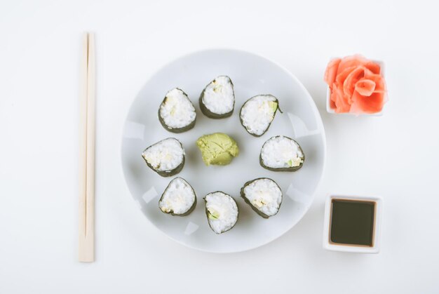 Opstelling van vegetarische sushi rolletjes van avocado en komkommer met gemberwasabi en sojasaus