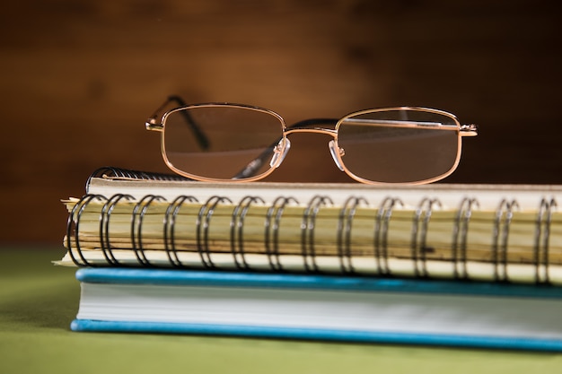 Optical glasses on notebooks on a green table