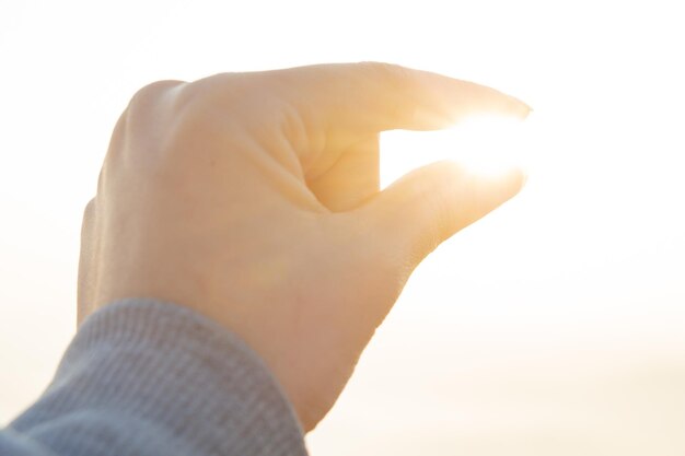 写真 空に照らして太陽を握る手の光学錯覚