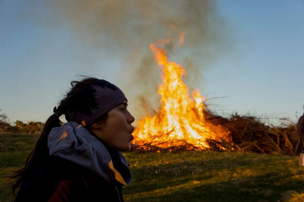 Фото Оптическая иллюзия женщины, дующей горящий огонь на поле против неба