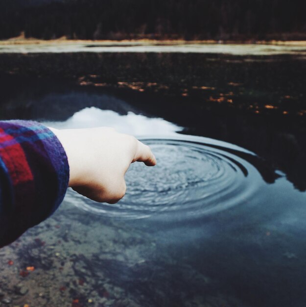 Foto illusione ottica di una persona che tocca l'acqua sul lago