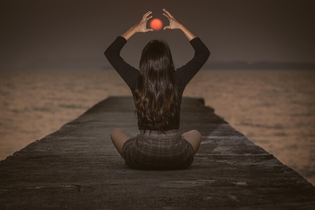 Photo optical illusion of woman holding sun at beach