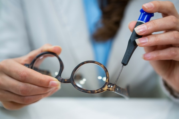 Optician repairing spectacles with tool