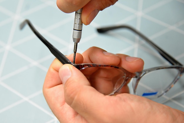 Opticien repareren en repareren van bril met schroevendraaier