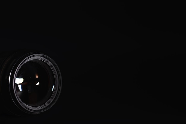 オペレーターの机の上のカメラへの光学。フォトレンズのガラスのフレア。写真家の技術と黒の背景。