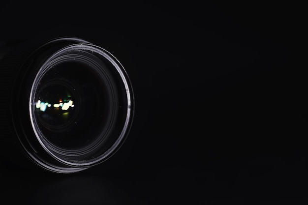 Optics to the camera on the operatorâs desk. flare in the\
glass of a photo lens. black background with the technique of the\
photographer.