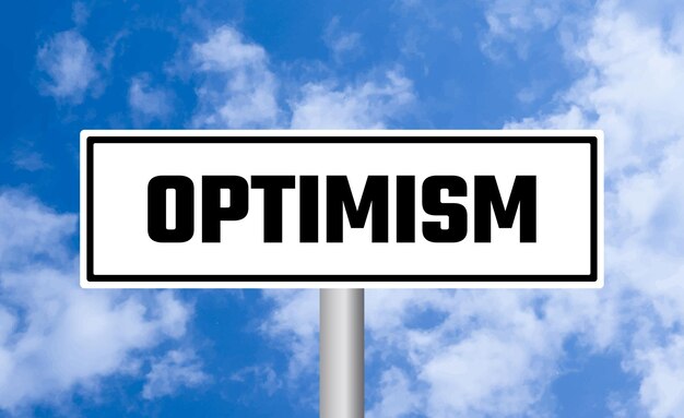 Optimism road sign on sky background