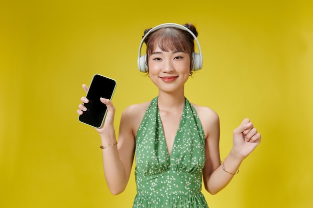 Оптимистичная довольная азиатка поет любимую песню в смартфонах, развлекается и наслаждается музыкой