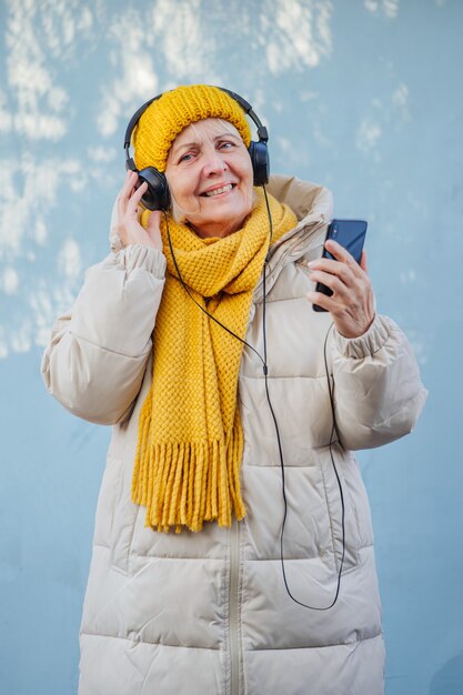 optimistic senior female listening to music and using smartphone