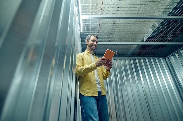 Optimistic young man looking at tablet in garage