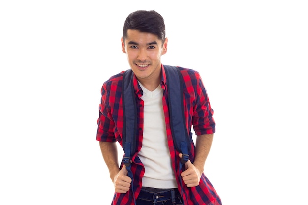 Optimistic young man with black hair in jeans white Tshirt and checkered shirt with blue backpack