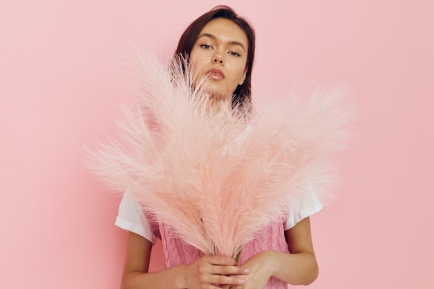 Optimistic young woman pink feathers in hand posing casual wear\
lifestyle unaltered