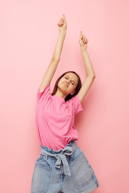 Оптимистичная молодая женщина в розовой футболке в повседневной одежде на изолированном фоне