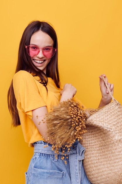 Optimistic young woman wicker bag in hand pink glasses isolated background