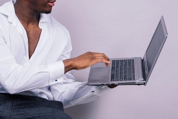 Optimistische Afro-Amerikaanse mannelijke student in casual shirt met behulp van laptop pc geïsoleerd