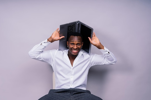 Optimistische Afro-Amerikaanse mannelijke student in casual shirt met behulp van laptop pc geïsoleerd