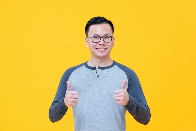 Optimistische Aziatische man in casual t-shirt glimlachend geven duimen omhoog