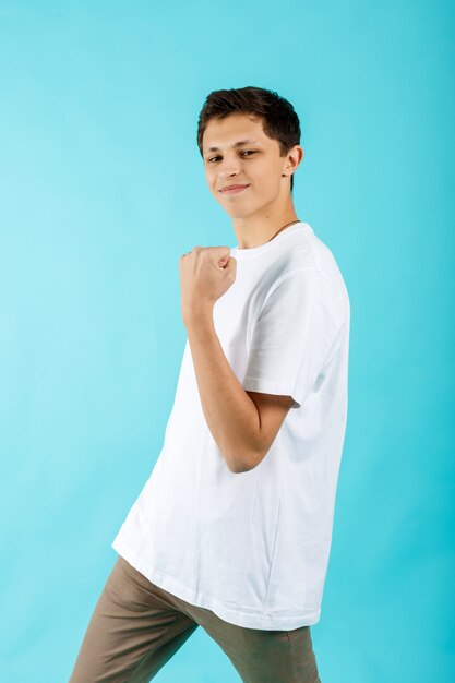 Optimistische man in een wit t-shirt maakt een winnend gebaar met zijn hand