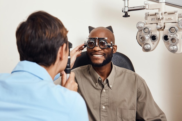 Optisch examen opticien of oogarts aan het werk testen visie of zicht van patiënt bij optometrist Gelukkig lachende jonge man zijn ogen controleren op bril of behandeling bij een oogarts in een kliniek