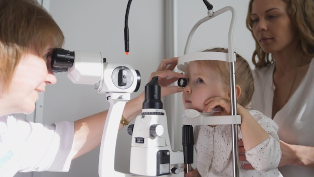 Optometrist checks little girls eyesight  mother and child in ophthalmologist room