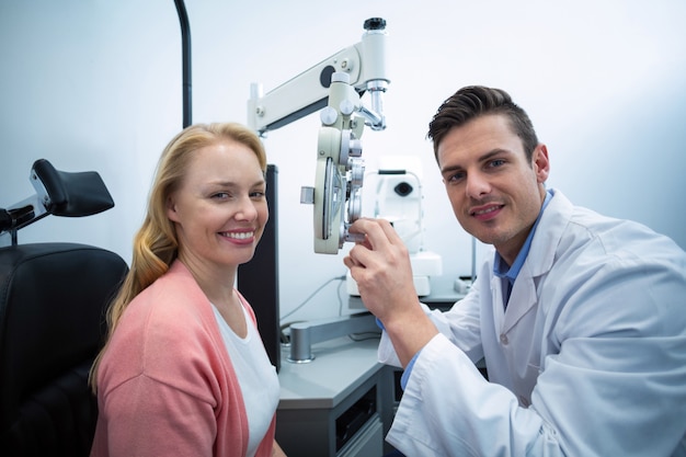 Optometrist examining female patient on phoropter