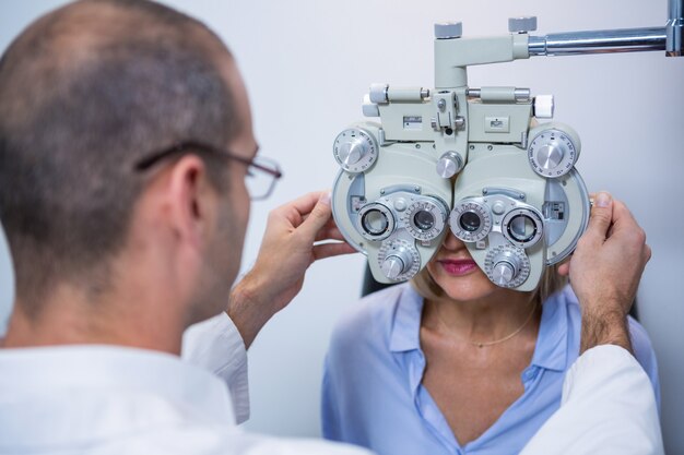 Optometrist examining female patient on phoropter