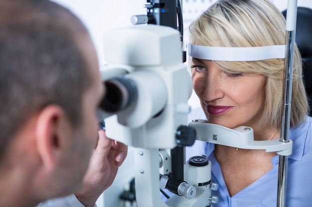 Optometrist examining female patient on slit lamp