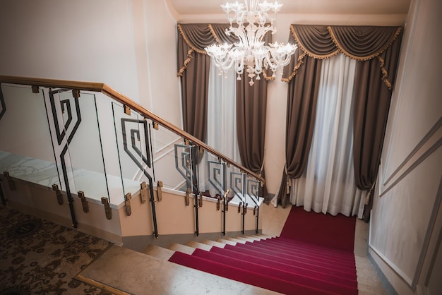 Opulent venetian style grand staircase with luxurious chandelier and red carpet