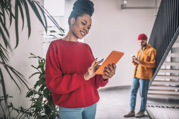 Opwinding. Zwarte vrouw in rood shirt met een tablet die opgewonden kijkt