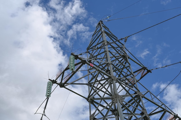 Opzoeken van stalen hoogspanningsmastconstructie met hoogspanningskabels tegen blauwe lucht