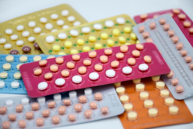 Oral contraceptive pill on pharmacy counter with colorful pills strips background