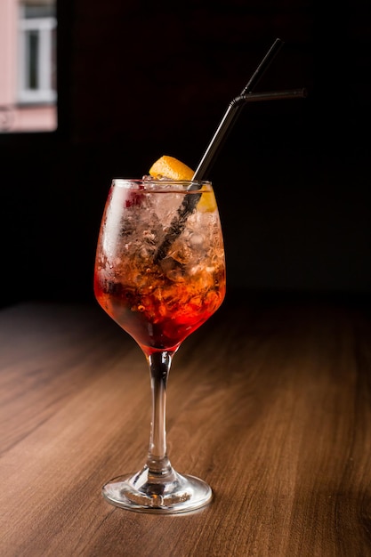 orange alcoholic cocktail Aperol Spritz with cherries orange peel on a dark background