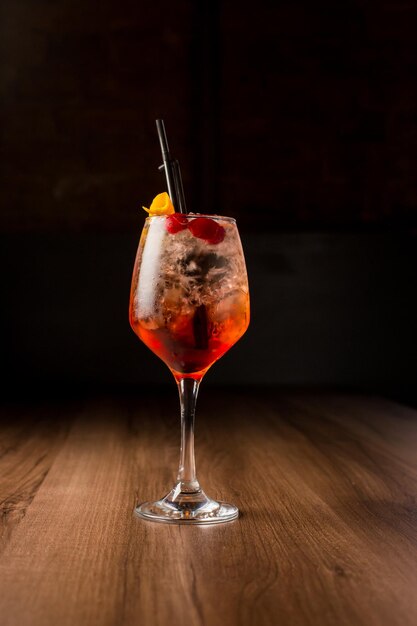 orange alcoholic cocktail Aperol Spritz with cherries orange peel on a dark background