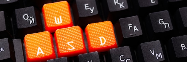 写真 黒のキーボードのオレンジ色の矢印キー、ゲーミングコンピュータのキーボードの上下左右のボタン