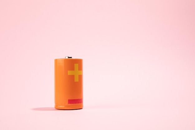 Orange battery on pink background energy concept