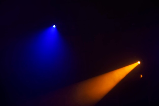 Orange beams of light from stage spotlights on a dark blue backgroundIllumination of the stage