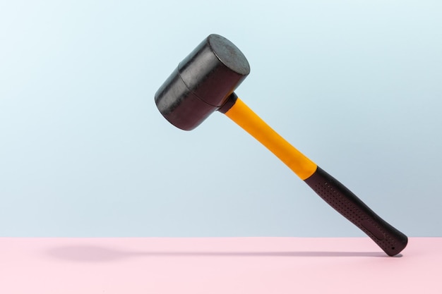Photo orange and black rubber hammer isolated on a cyan pink background