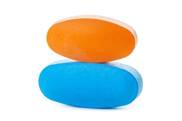 Orange and blue pills on white surface