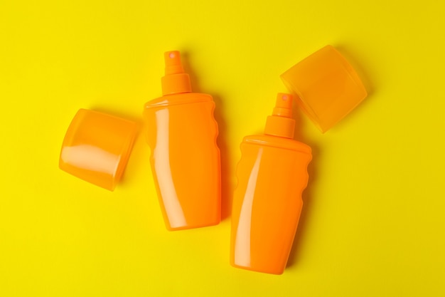 Orange bottles of sunscreen on yellow