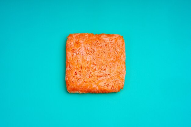 Orange bricks of frozen grated carrots. Procurement of frozen food. Semifinished.