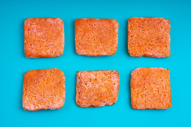 Orange bricks of frozen grated carrots. Procurement of frozen food. Semifinished.