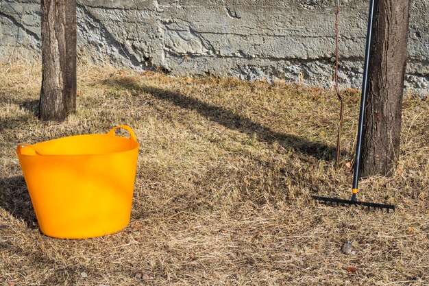 Orange bucket and black rake gardening equipment and tool