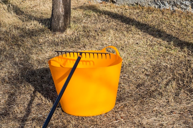 Orange bucket and black rake gardening equipment and tool