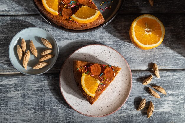 Orange cake on a gray wooden background. Hard light. contrast, low key. Top view, flat lay,