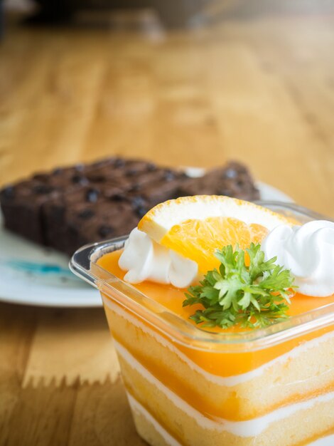 orange cake topped with piece of orange in plastic cup