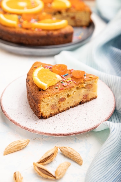 Orange cake with almonds and a cup of coffee on a white concrete background Top view selective focus