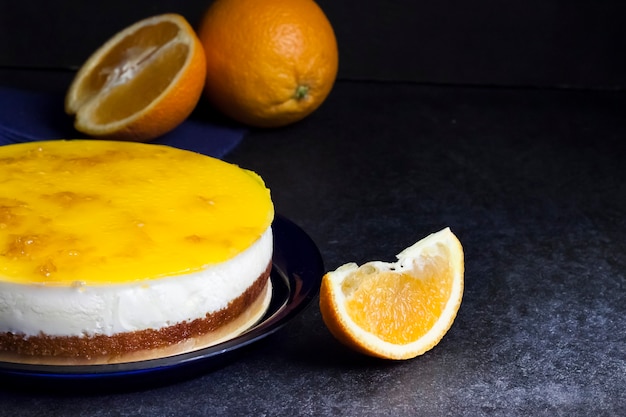 Torta all'arancia con mousse alla crema e gelatina all'arancia su fondo scuro