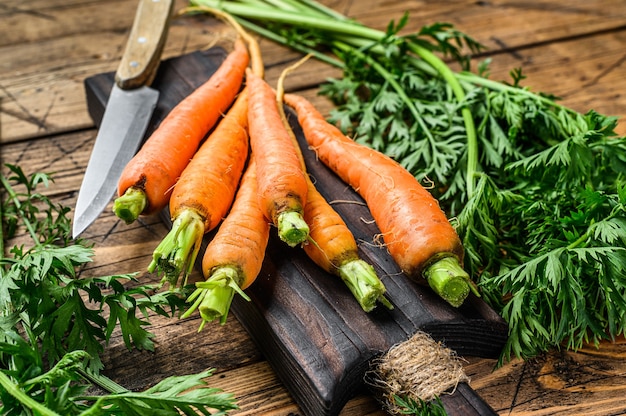 Orange carrots with leaves on a cutting board